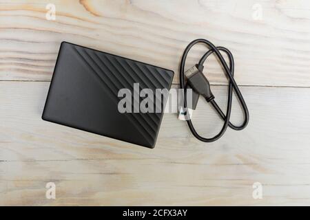 External hard drive for storing memory with wire on wood table background Stock Photo