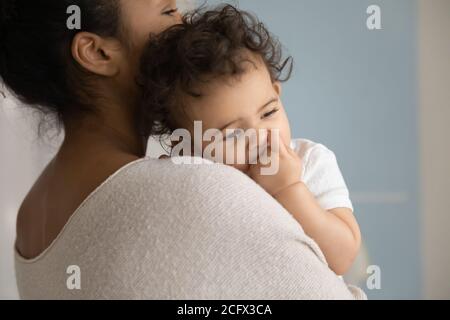 Affectionate caring young mixed race mommy holding sleeping kid.
