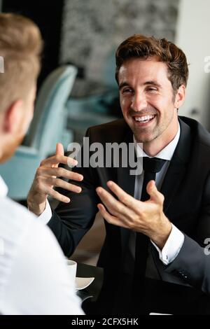 Colleagues and friends. Two cheerful businessmen drinking coffee and talking to each other Stock Photo