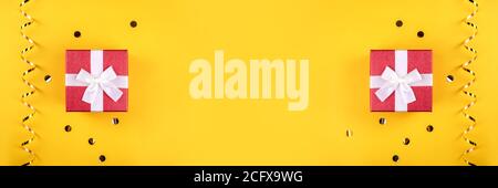 Banner made from red gift boxes on yellow background with golden confetti. Stock Photo