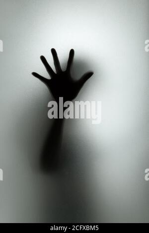 Ghost concept shadow of a woman behind the matte glass blurry hand and body soft focus Stock Photo
