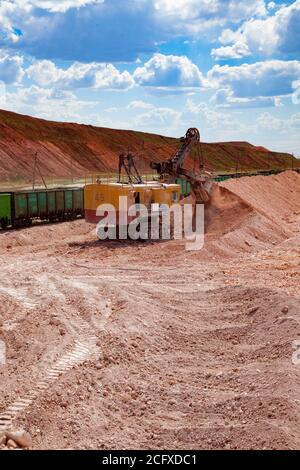 Aluminium ore mining and transporting. Open-cut mining of Bauxite clay. Loading ore with electrical excavator in rail wagons. Stock Photo