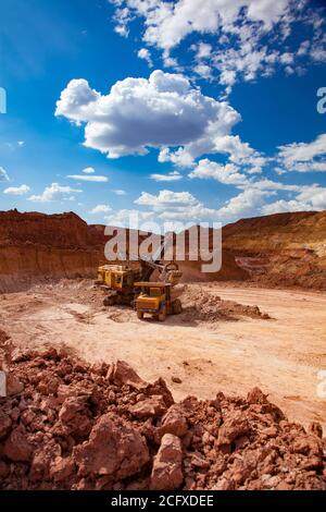 Aluminium ore mining and transporting. Bauxite clay open-cut mining. Excavator loading Belaz dump truck with ore. Stock Photo