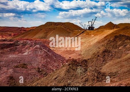 Aluminium ore quarry. Bauxite clay open-cut mining. Walking draglines excavator. on blue sky with clouds. Panorama view. Stock Photo