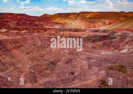 Aluminium ore quarry. Bauxite clay open-cut mining. Color heaps of empty stones. Blue sky with clouds. Panorama view. Stock Photo