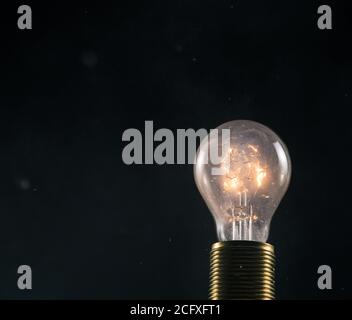 Burning old light bulb on black backround. Concept of new idea and brain storming. Stock Photo