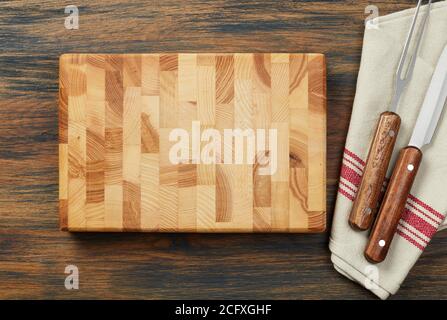 Cutting board, fork and knife on wooden table Stock Photo