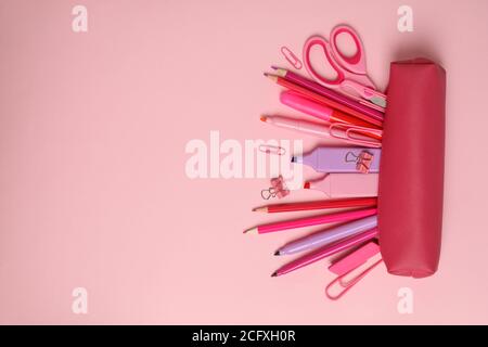 Pink pencil case with different supplies on pink background Stock Photo