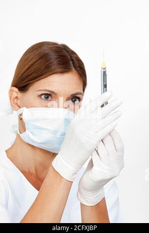 Dentist with a face mask pulls up a syringe Stock Photo