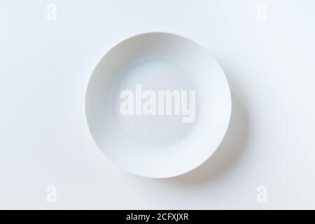 Empty ceramic round plate isolated on white background. White plate placed on white background. Top view. Flat lay. Stock Photo