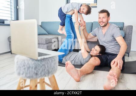 Mother balances child on her feet in video chat online on laptop computer Stock Photo