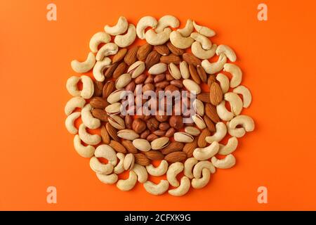 Circle made of different nuts on orange background. Vitamin food Stock Photo