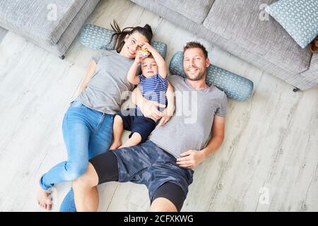 Parents and children lie on the floor in the living room as a happy small family Stock Photo