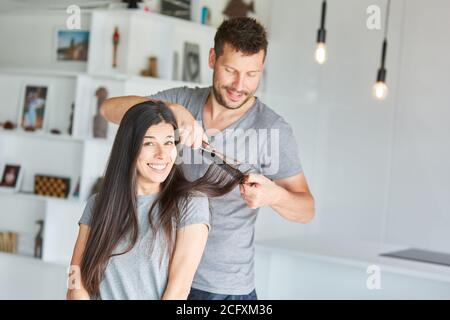 Man cutting hair himself for his wife at home Stock Photo