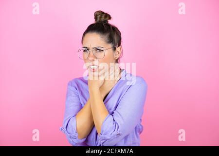 Young beautiful woman wearing glasses over isolated pink background touching painful neck, sore throat for flu, clod and infection Stock Photo