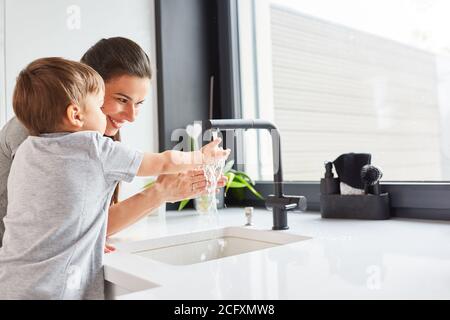 Mother helps child wash hands with soap as hygiene against Covid-19 Stock Photo