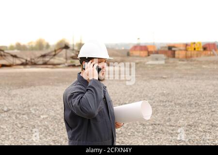 Caucasian foreman speaking by VHF walkie talkie and papers on construction site. Stock Photo