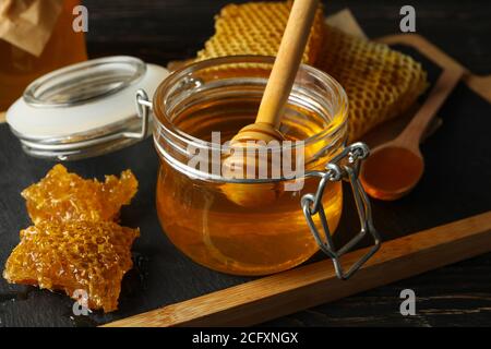 Composition with honeycombs, honey, jars and dipper on wooden background Stock Photo