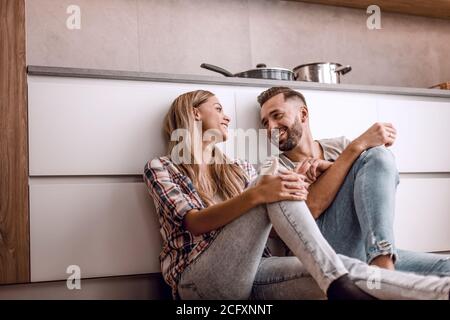 happy couple discussing something sitting on the kitchen floor Stock Photo