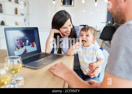 Grandma congratulates her birthday with cake on the laptop computer via video chat Stock Photo