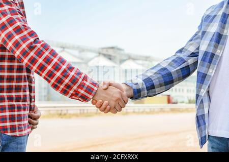 Businessmen shake hands against silos. Agriculture business Stock Photo