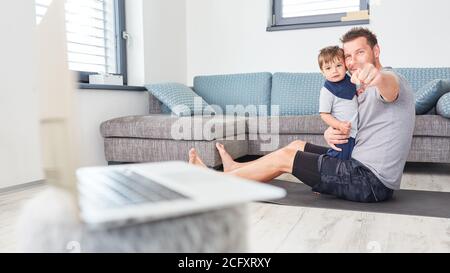 Father and son playing in living room with laptop computer in foreground Stock Photo