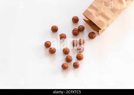 Flat composition with macadamia nuts scattered from paper bag on a white table Stock Photo
