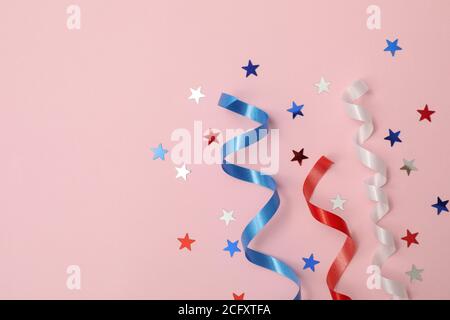 White, red and blue curly ribbons and stars on pink background Stock Photo