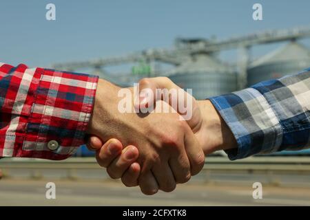 Businessmen shake hands against silos. Agriculture business Stock Photo