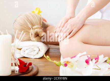 Female hands do massage on girl shoulders, lying on table Stock Photo