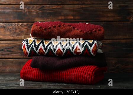 Pile of different sweaters on wooden background Stock Photo