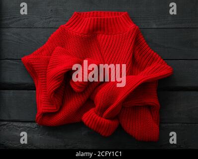 Red knitted sweater on wooden background, top view Stock Photo