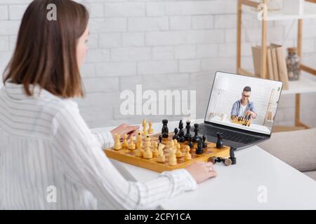 Online chess at home. Girl and guy play on board games using laptop Stock Photo
