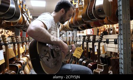 Montreal, Quebec, Canada - 25 June, 2018: Man trying the guitar in a guitar store. Stock Photo