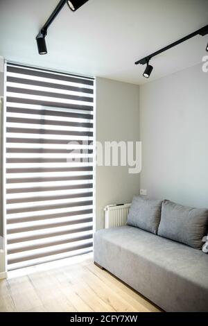 Gray sofa in a small room. Big window. The concept of interior, home and comfort. Stock Photo