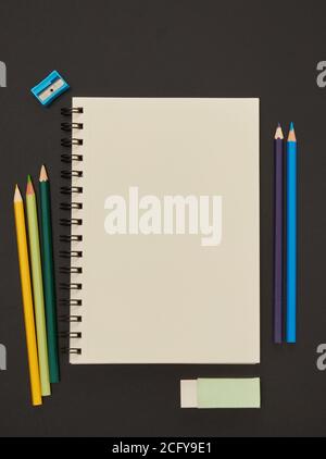 Notebook and multi-colored pencils on blackboard Stock Photo