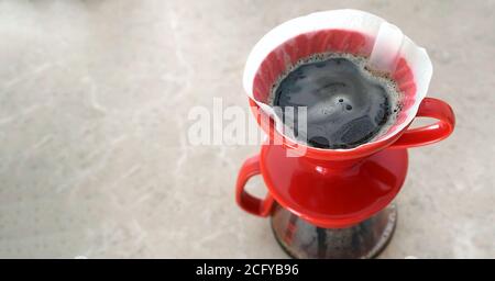 Pourover. v60. Delicious aromatic coffee filter is brewed in a red ceramic dropper. Close-up, view from above Stock Photo