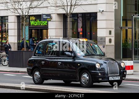 London, England, UK - December 31, 2019:   Typical black London cab in city streets. Traditionally Taxi cabs are all black in London but now produced Stock Photo