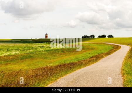 view on Pilsum lighthouse in East Frisia with tourists walking around the dike and taking photographs Stock Photo