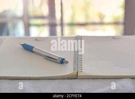Close up of pen in notebook on office desk with blurry background. Stock Photo
