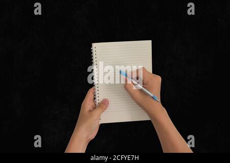 Hand holding pen, with a blank notes over blackboard background. Design concept Stock Photo