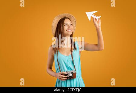 Happy young woman with camera holding paper airplane Stock Photo