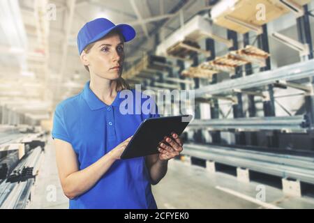 stock management - young female warehouse employee with digital tablet at construction material store Stock Photo