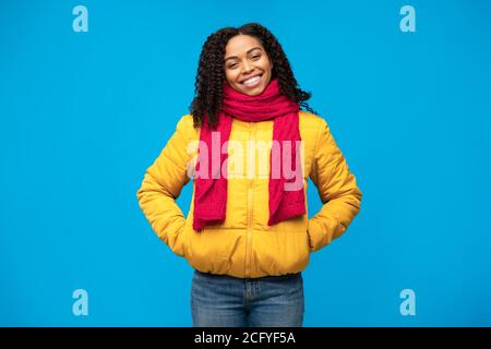 African Girl In Winter Jacket Smiling Standing Over Blue Background Stock Photo
