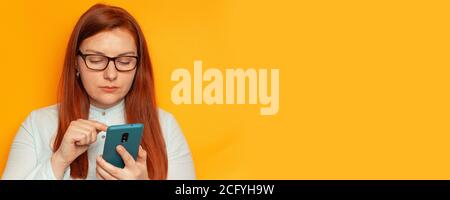 Business woman uses smartphone and standing on a yellow background wall Stock Photo