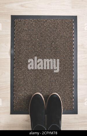 Womens black suede shoes on a rug on the floor in the hallway. Stock Photo