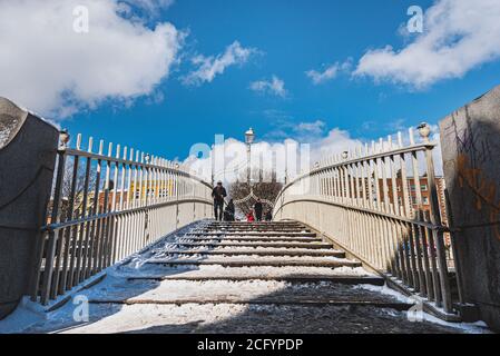 Ha' penny Bridge covered with snow. This pedestrian overpass is a popular historical landmark across River Liffey and conveys a sense of community Stock Photo
