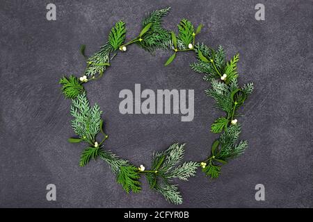 Winter solstice wreath with mistletoe & cedar cypress  fir on grunge grey background. Christmas & New Year festive decoration. Top view, flat lay. Stock Photo