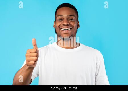 Cheerful African American Guy Gesturing Thumbs-Up Posing Over Blue Background Stock Photo