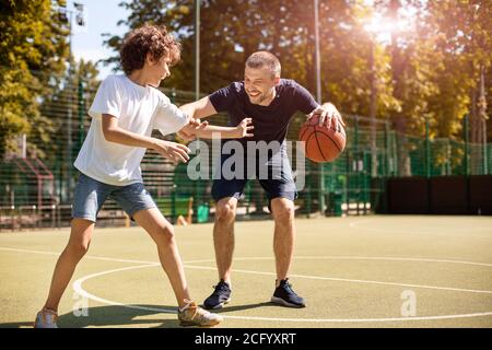 Mature man teaching boy how to play basketball Stock Photo